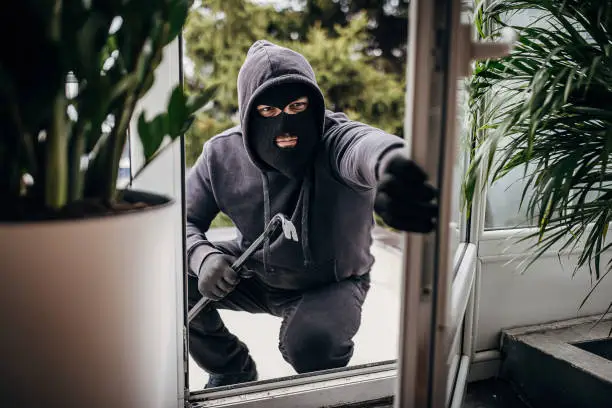 Image of a burglar breaking into a house